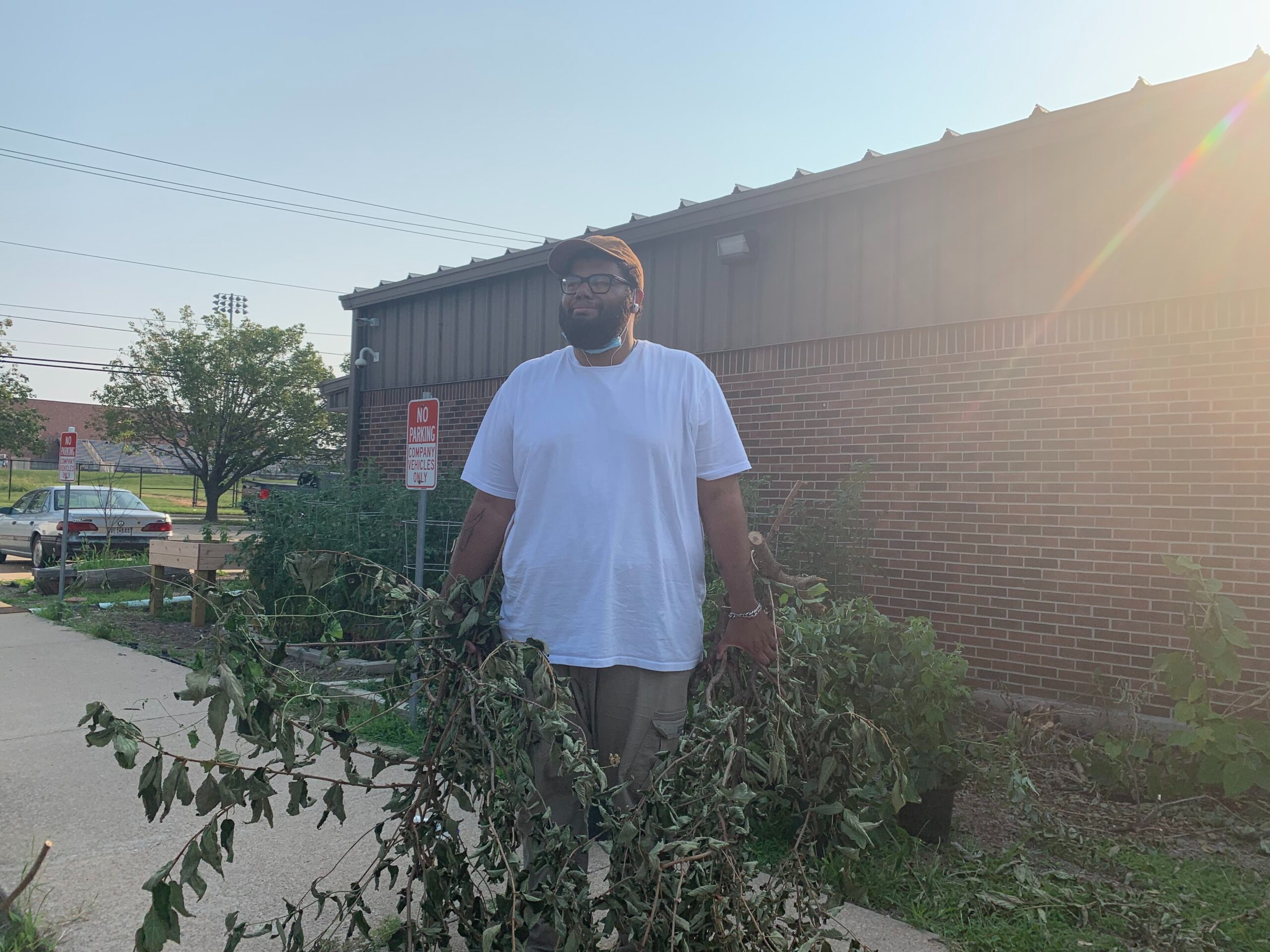 Headshot of Matthia Rickets holding some greenery he cut down