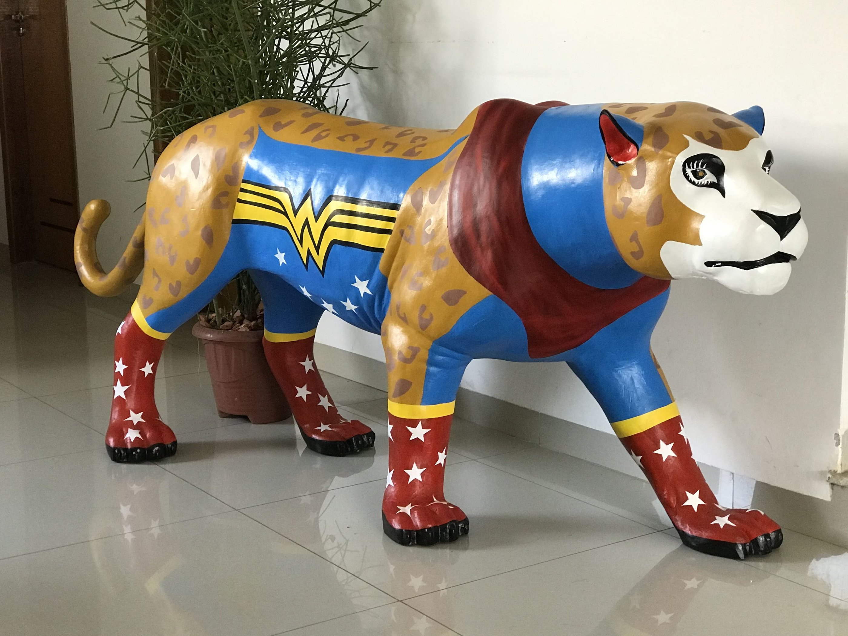 Detalhe da pintura da Onça Maravilha com padrões e cores vibrantes, alusões à Mulher Maravilha.