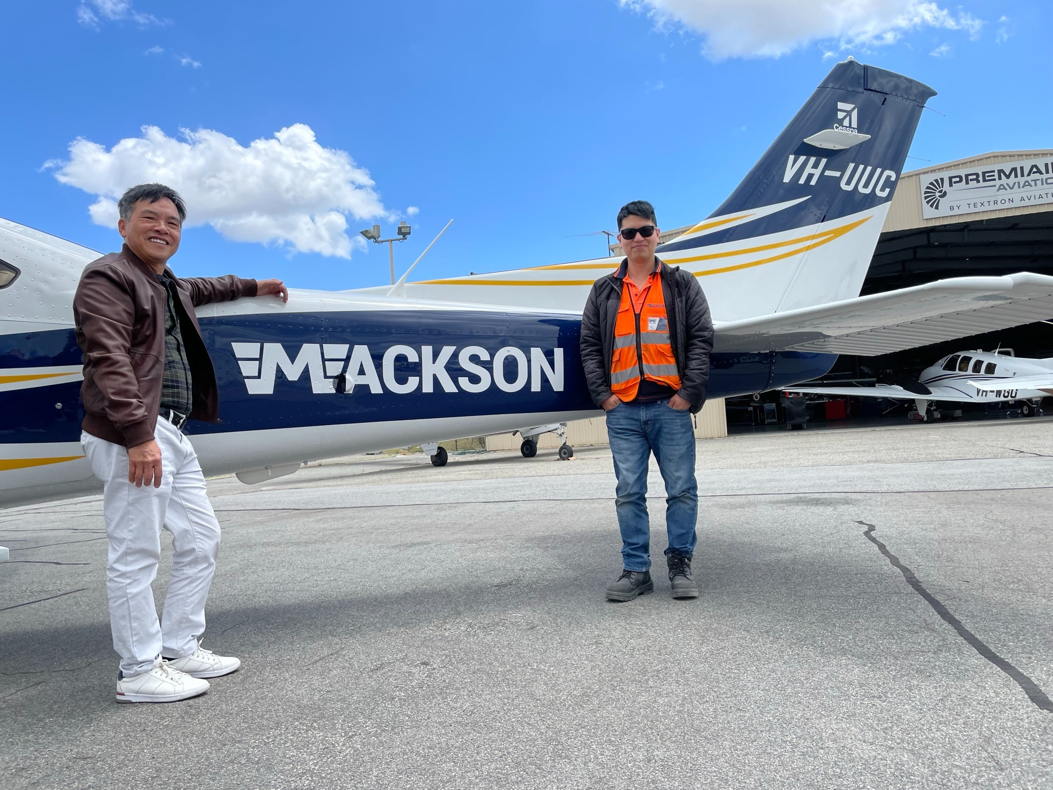 a man standing next to a plane with a man in a vest