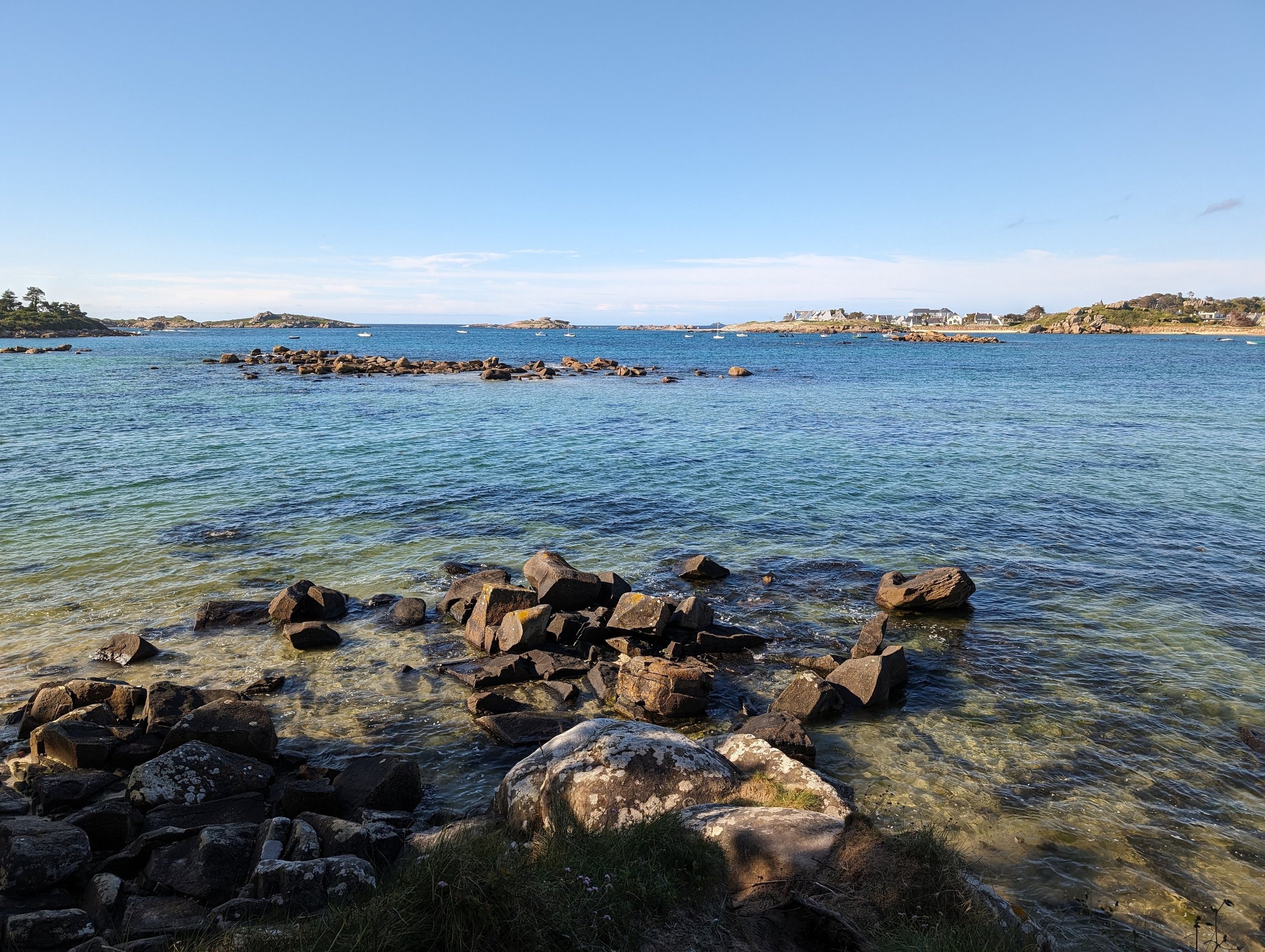 bord de mer, Eau cristalline, rochers et îlots sous un ciel bleu, offrant un paysage côtier apaisant