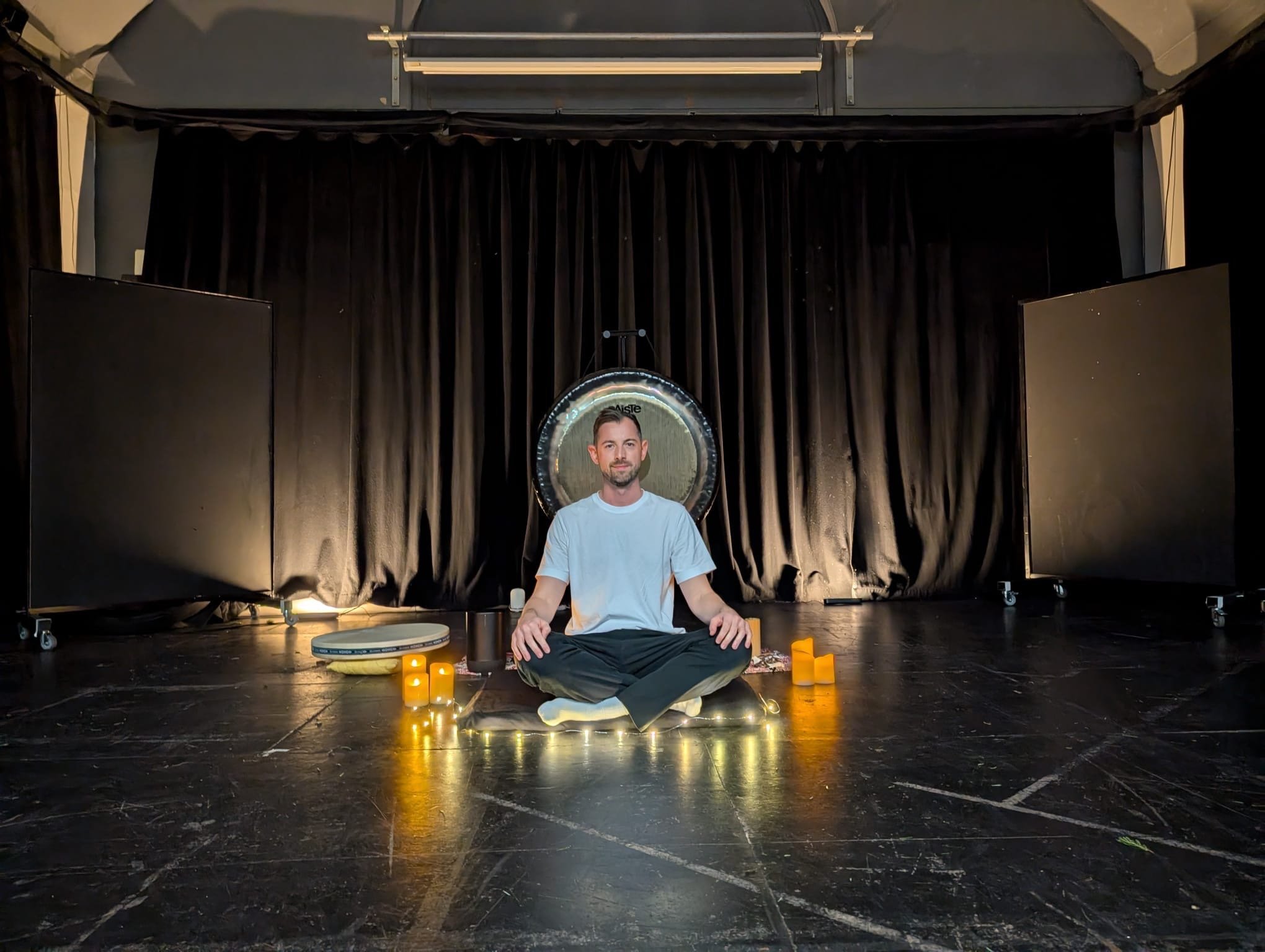 a man sitting in front of a gong leading a relaxing sound bath