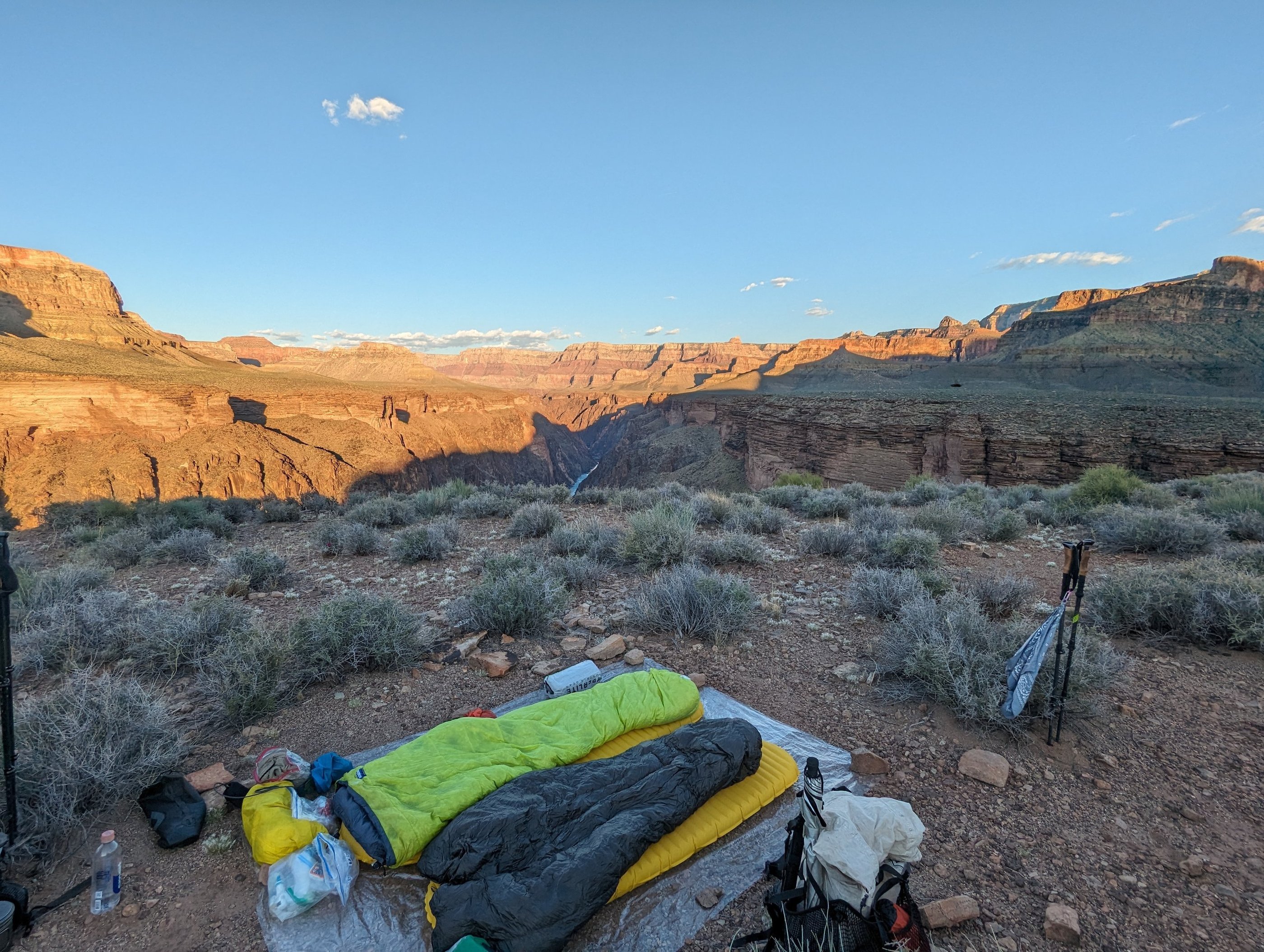 A cowboy camp setup with a Feathered Friends sleeping bag near a cliff in the Grand Canyon.