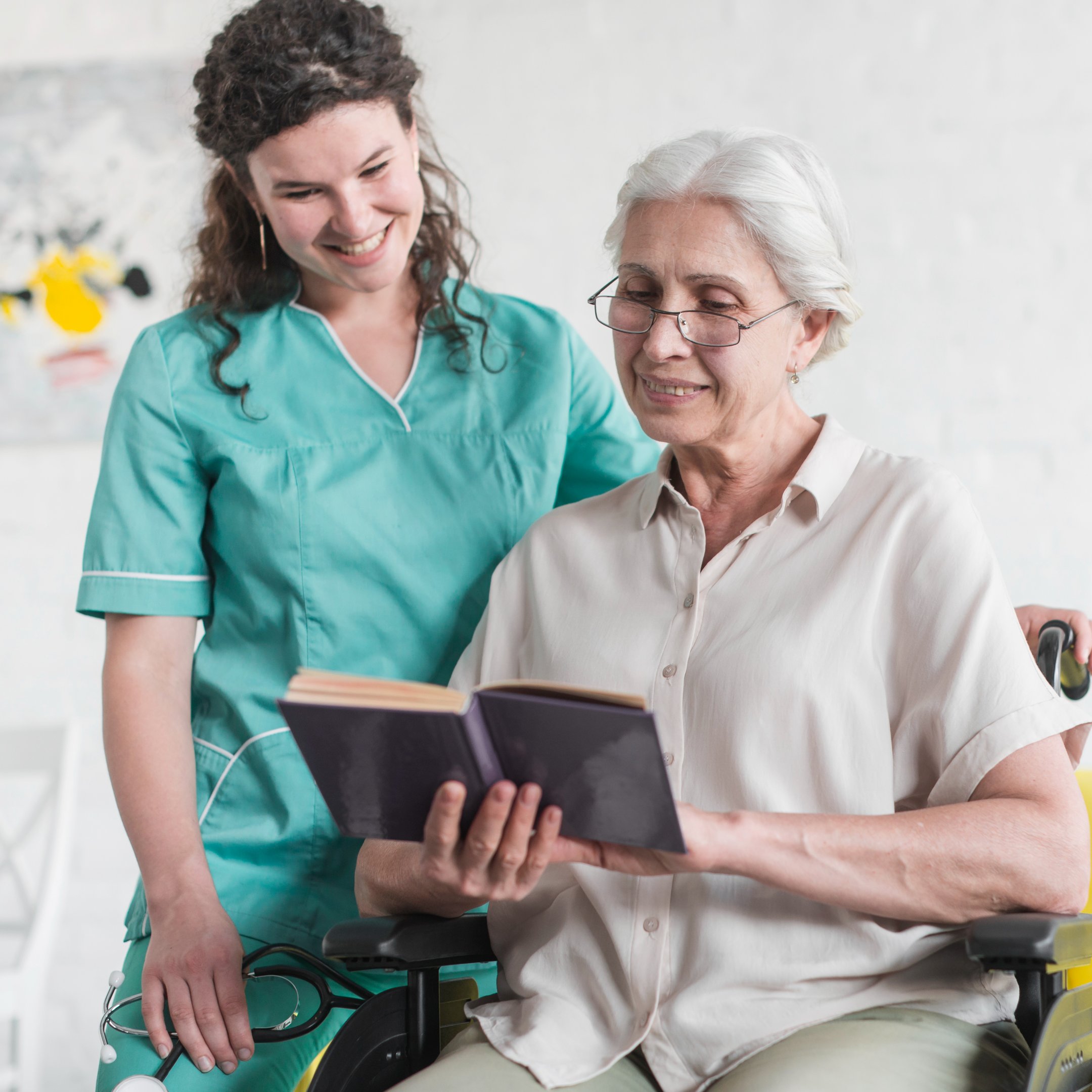 a senior woman reading a book with her caregiver