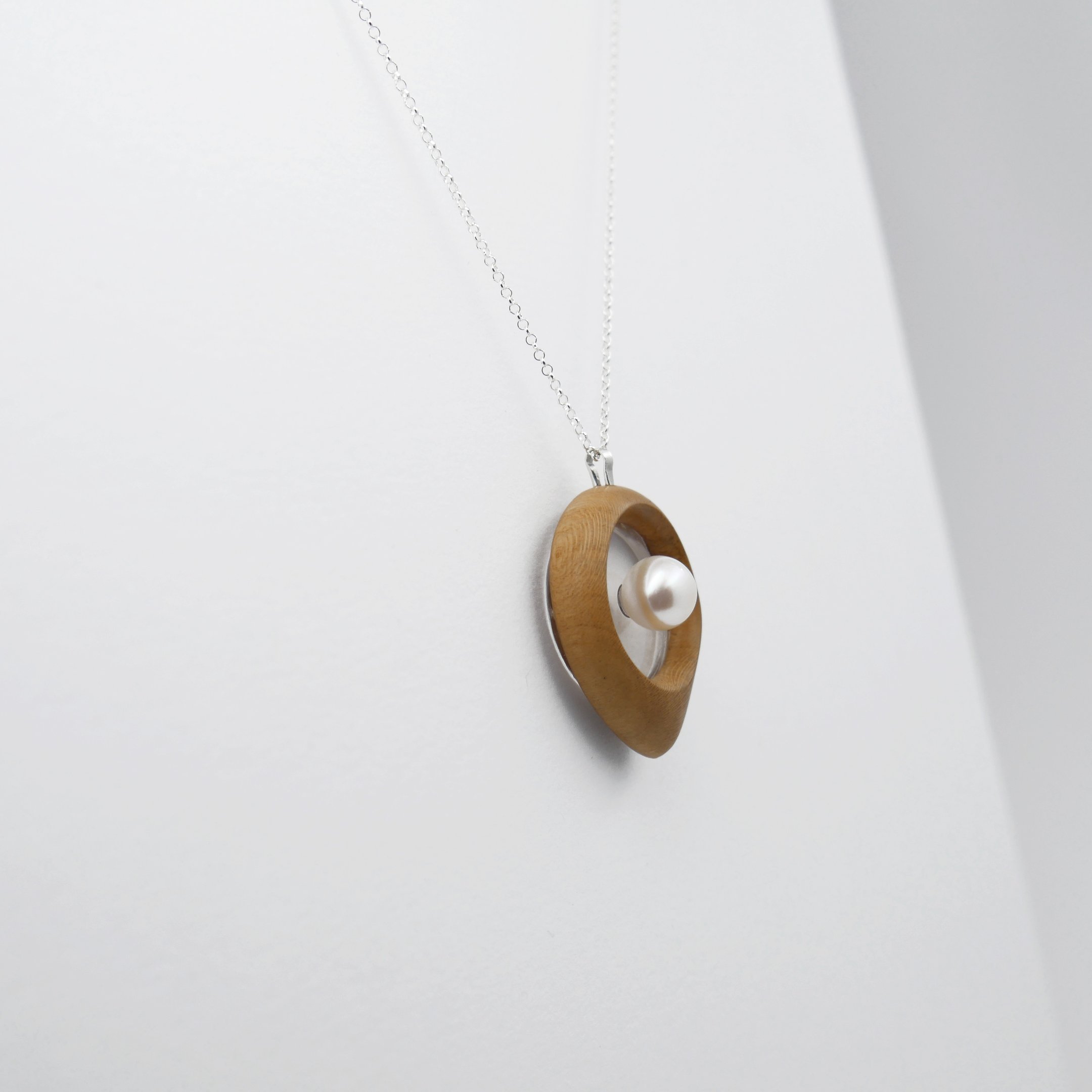 Handmade wooden pendant necklace with a white pearl on a silver chain.