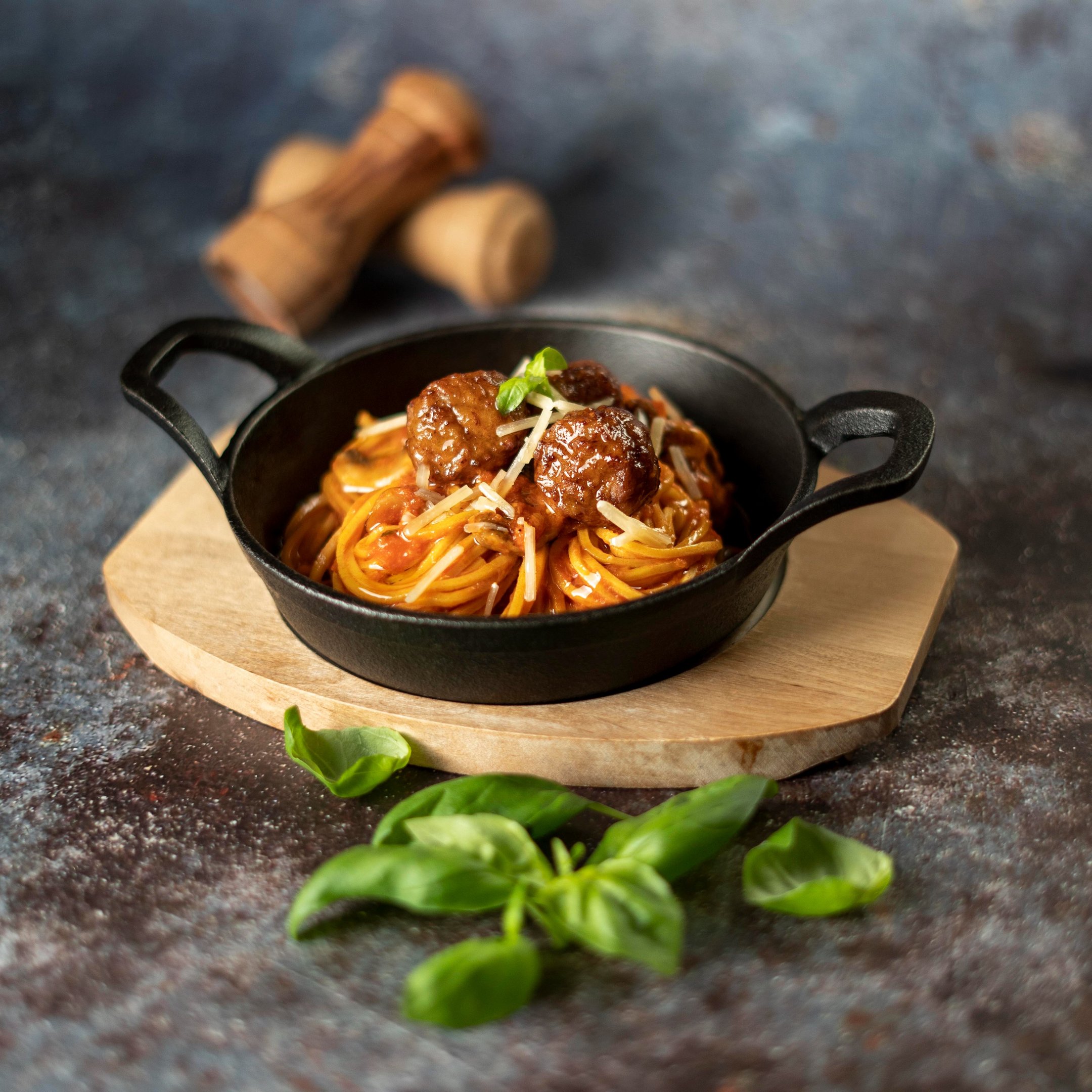 Professional food photography of spaghetti meatballs served in a iron pan - menu content creation