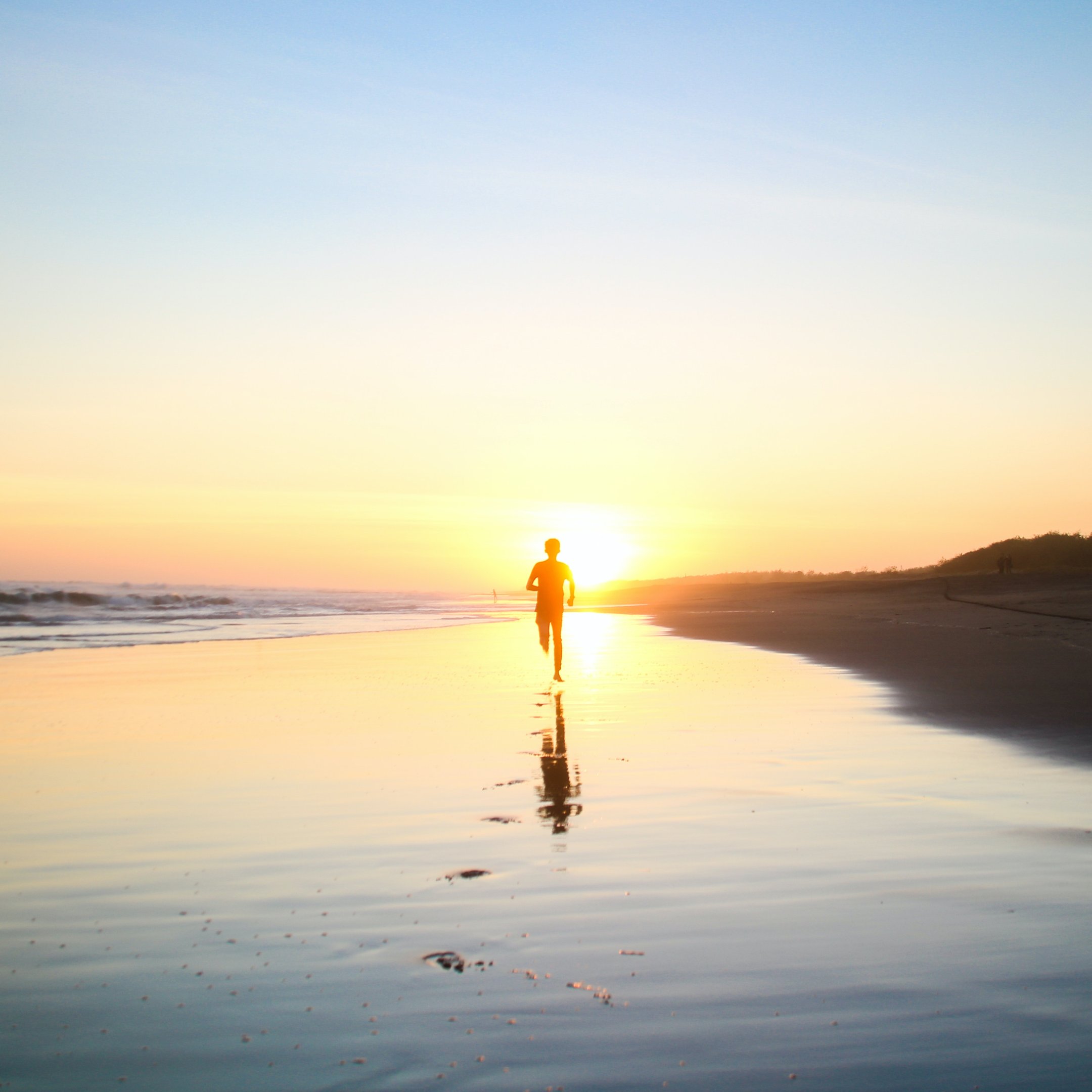 a person walking on a beach at sunset