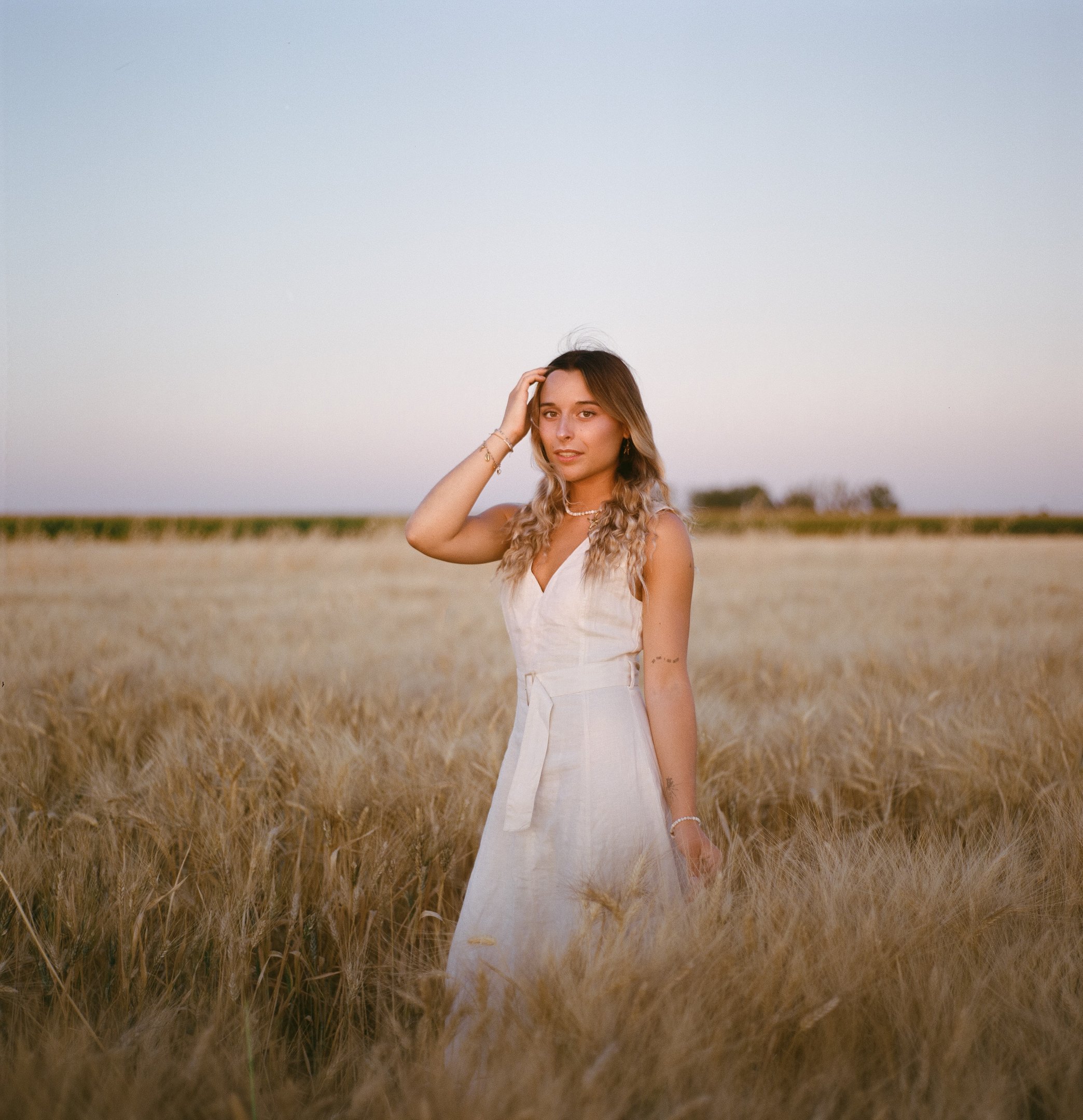 Une marié prend la pose dans un champ de blé. Photo prise à l'argentique avec la portra 400