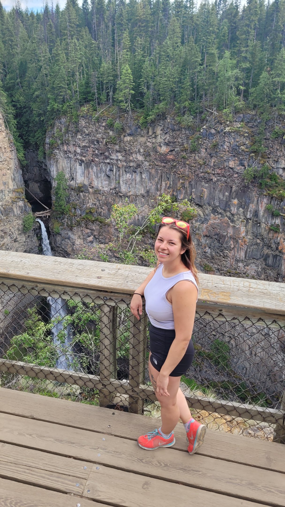A smiling woman wearing pink sunglasses and a purple shirt