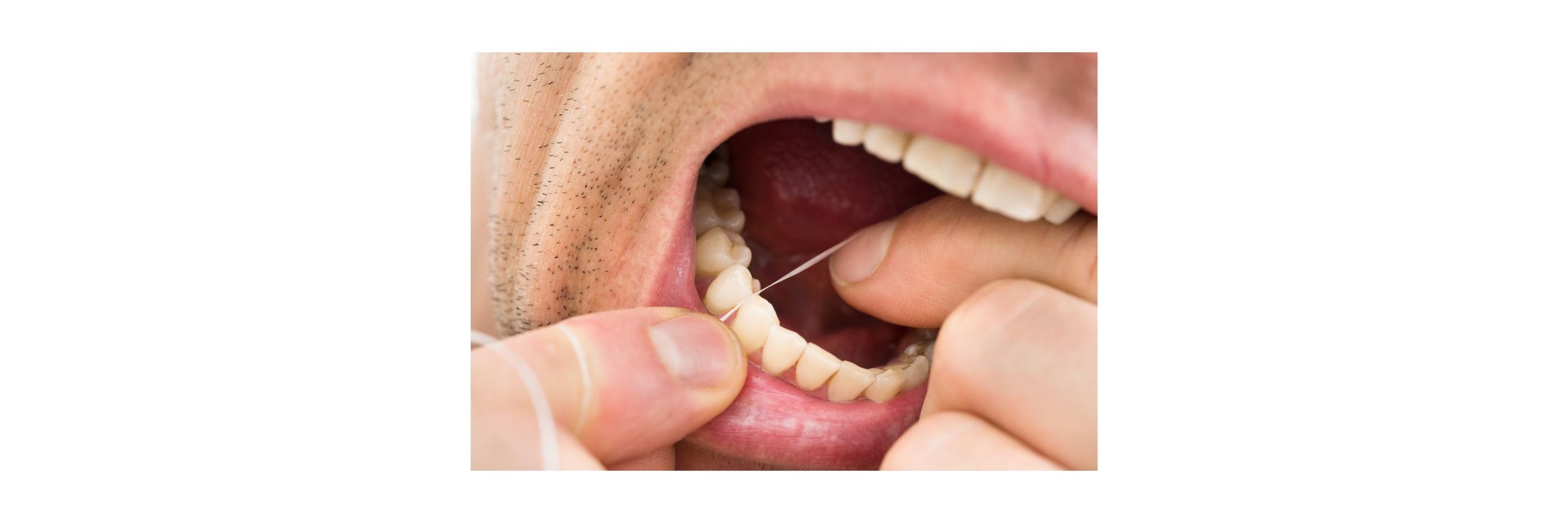 a man cleaning his teeth using dental floss