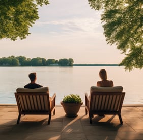 a couple sitting on a patio with a view of a lake