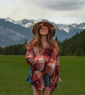 a woman in a plaidered blanket in front of a mountain in Banff