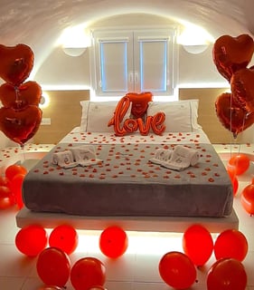 Romantic surprise room setup with heart-shaped balloons for an anniversary celebration.