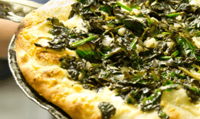 a pizza with spinach and cheese on a pan
