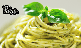 a bowl of pasta with pesto and basil leaves