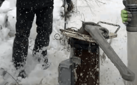Large wrench opening well head in winter.