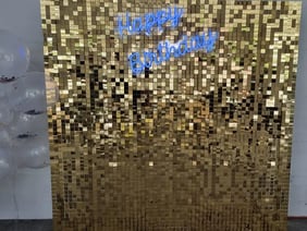Blue happy birthday neon sign on a gold shimmer wall for Tipene's daughter in Logan.