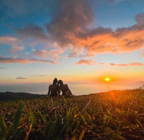 Eva and Manon watching the sunset in Tahiti, with the ocean in the background.
