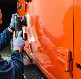 a man in a blue jacket and gloves is buffing a car at fix collision center