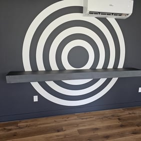 Game room with a black feature wall showcasing a striking bullseye design and a functional floating shelf for added style