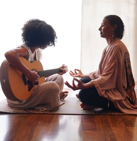 a woman sitting on a mat with a guitar and a guitar