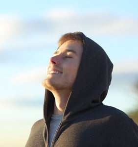 Un chico con capucha respirando al aire libre representando que ha conseguido salir de la adicción