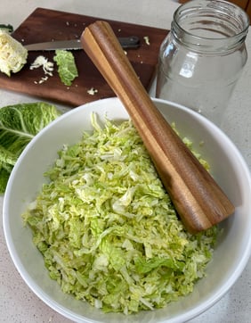 cabbage in a bowl with a wooden tamper