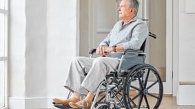 Elderly man in wheelchair looking out window in bright, peaceful home setting