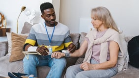 Healthcare worker checking elderly woman's blood pressure at home visit