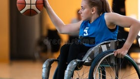 Female wheelchair basketball player in action on indoor court, dribbling ball