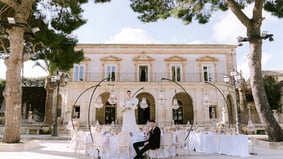 villa adibita a matrimonio con la sposa sul tavolo in piedi e lo sposo seduto su una sedia