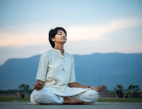 a woman sitting on a mat mat in a field doing meditation