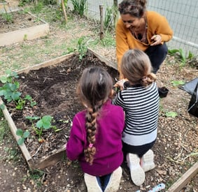 animatrice sensibilisant des enfants à l'environnement par la création d'un potager pédagogique