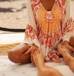 a woman sitting on a blanket doing reiki on a patient's feet