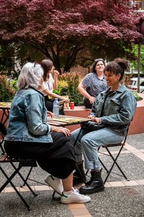 A group of women seated outdoors in a park, chatting and smiling