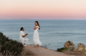 a woman proposing a woman on a cliff overlooking the ocean