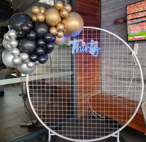 White circle mesh backdrop with a mini baloon garland and Thirty neon sign at the Chatswood Hill Tavern