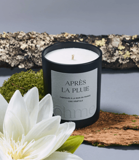 a fall scented candle with a white flower on a table
