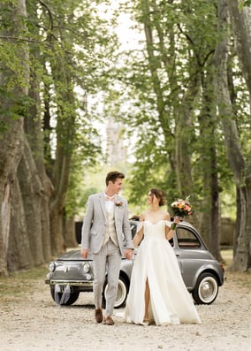 Wedding couple walking under trees with vintage Fiat 500 — South of France wedding photographer cost