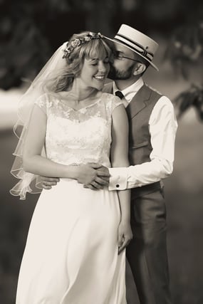 Braut und Bräutigam in eleganter Hochzeitskleidung umarmen sich im Freien.