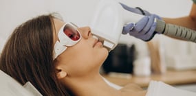 a woman in eye protection getting laser hair removal treatment