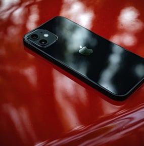 iPhone Km0 negro sobre una superficie roja brillante, resaltando su diseño premium y alta calidad.