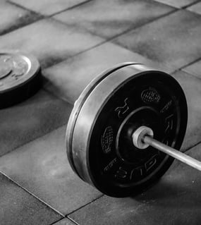 Greutăți contrastante, alb și negru, pe pardoseala sălii.