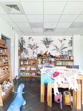 Réalisation du magasin de jouets avec vue sur du papier peint fleuri et des mobiliers en bois