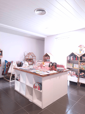 Aménagement du magasin de jouets avec des étagères et un plan de travail en bois et murs blancs