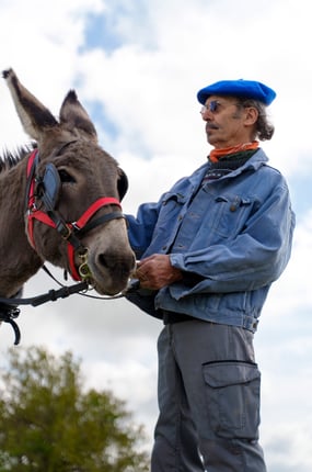 a man in a blue jacket and hat with a donkey