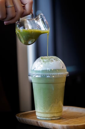 a person pouring a drink into a cup