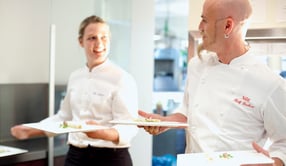 Ralf Zacherl holding two plates looking at a waitress.