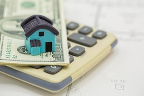 a house model of a house sitting on top of a calculator