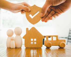 a person holding a piece of wood with a house in the background