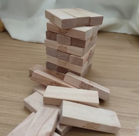 Jenga tower made of wooden blocks on a wooden surface, with several fallen pieces around it.